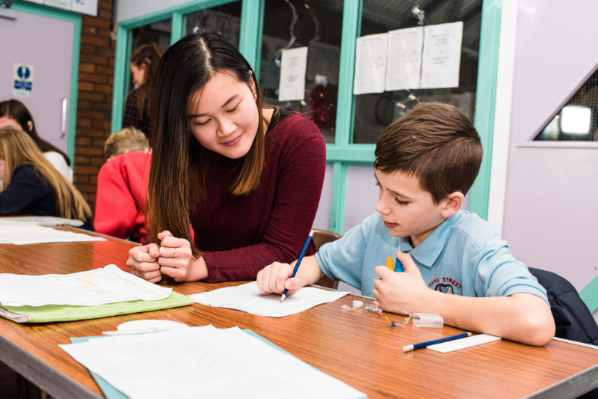 A university student helping a young boy with his homework